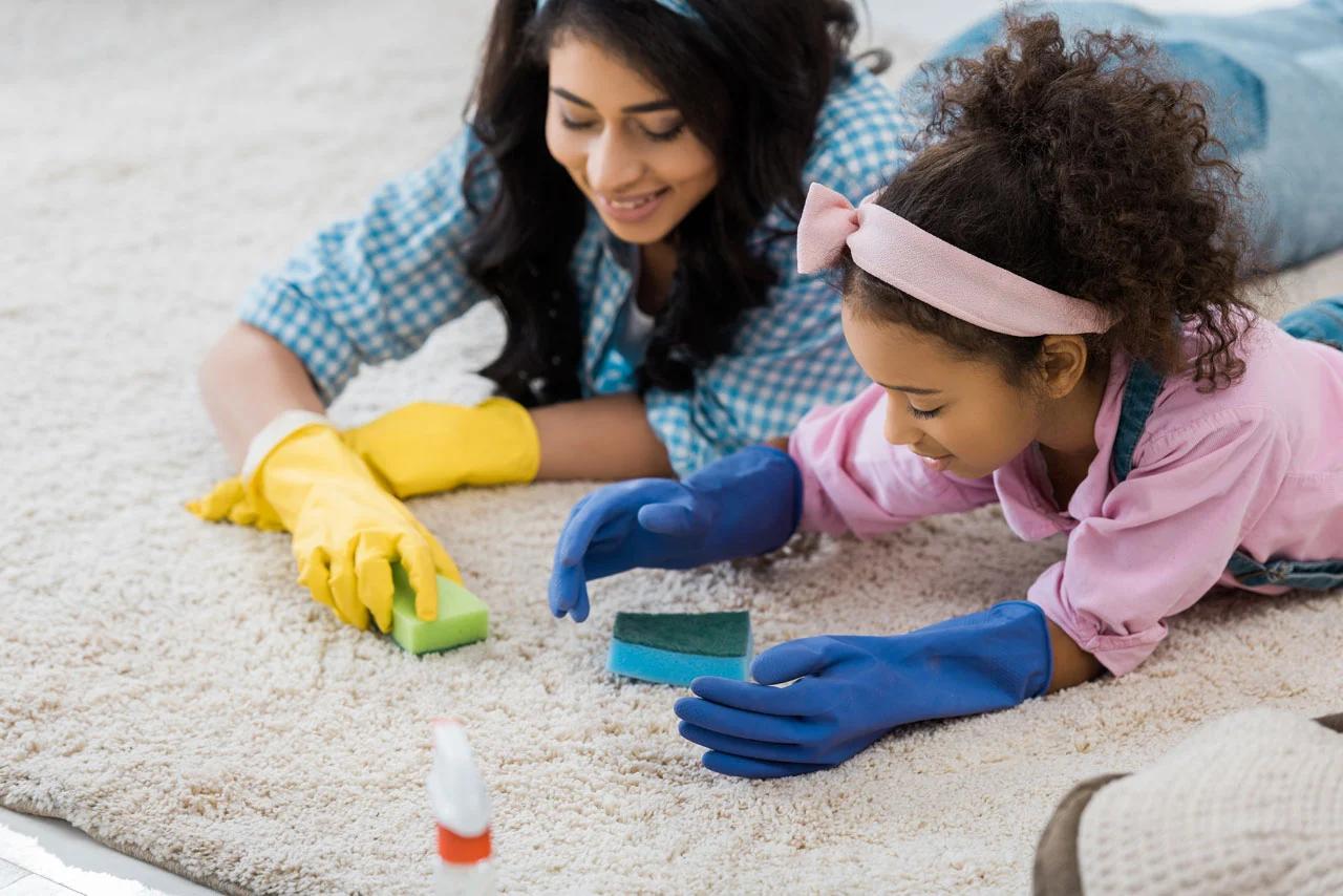 woman and little girl cleaning carpet with sponges.